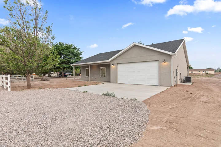 Exterior showcasing a stucco finish, attached garage with a panel door, concrete driveway, and black asphalt shingles