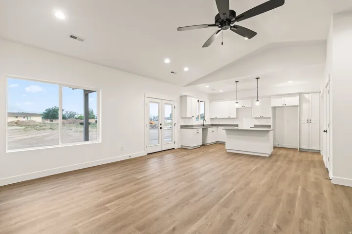 Open-concept living area featuring wood-finish flooring, a vaulted ceiling, and a modern ceiling fan