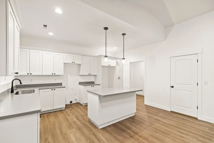 Contemporary kitchen featuring white cabinetry, grey countertops, and wood-finish flooring