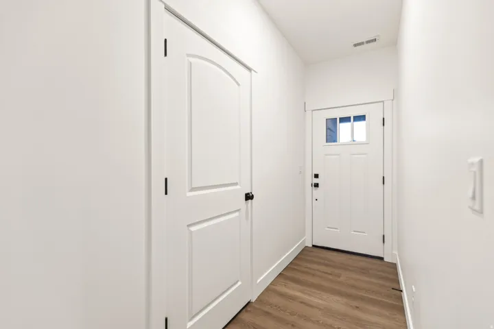 Entryway featuring a white door with upper glass panes, bright white walls, and wood-finish flooring
