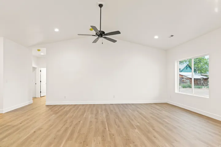 Expansive room featuring vaulted ceilings, light wood-finish flooring, recessed lighting, and a modern ceiling fan