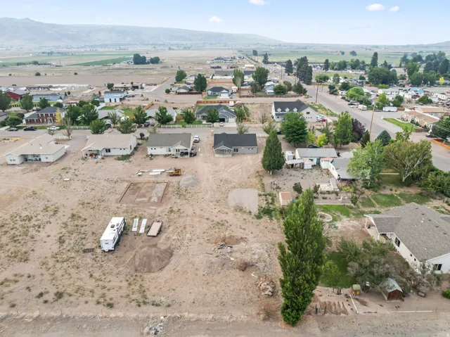 Expansive undeveloped land parcel featuring a level topography, mature trees, and visible building foundations