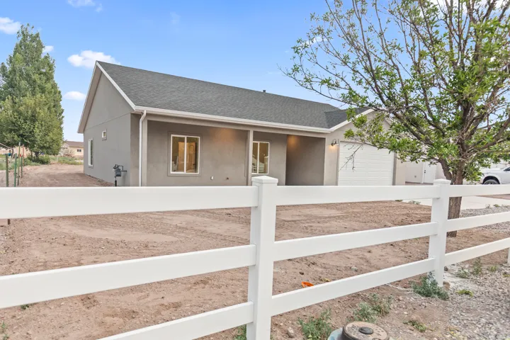 Contemporary ranch-style residence featuring a gray stucco exterior, white trim, and a dark shingle roof