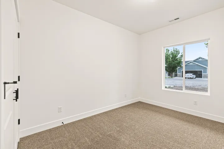 Neutral wall finishes, plush carpeting, bright white baseboards, and a white interior door with black hardware
