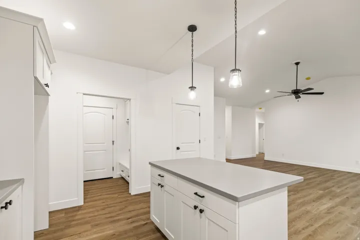 Kitchen island with light gray countertop, white cabinetry, and matte black hardware