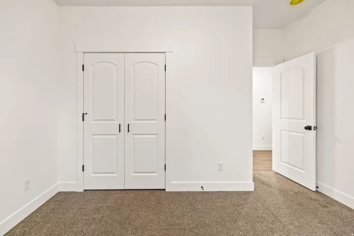 Interior room featuring neutral carpeting, white walls, and white baseboards