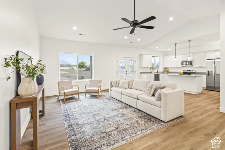Vaulted ceilings, wood-finish flooring, recessed lighting, ceiling fan, and white cabinetry with island seating