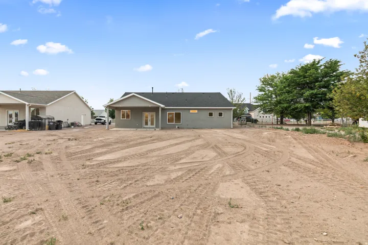Expansive rear yard with a newly constructed residence featuring a gray exterior finish and multiple windows