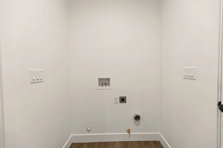 Dedicated laundry area featuring a wood-finish floor and white baseboards