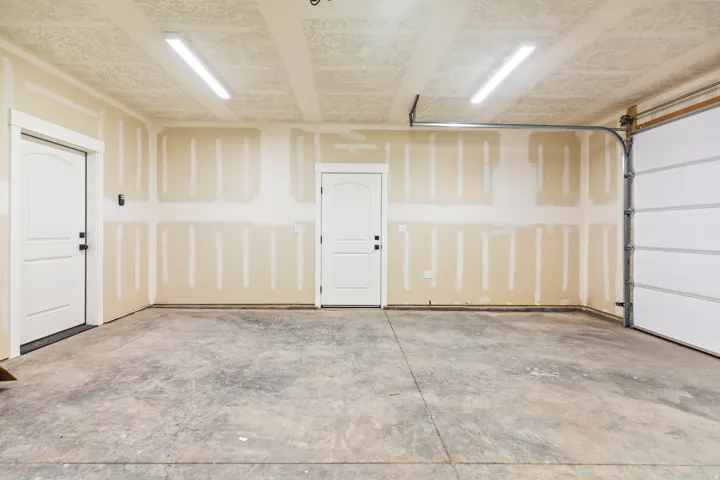 Spacious garage featuring a concrete floor, two interior access doors, and a paneled garage door