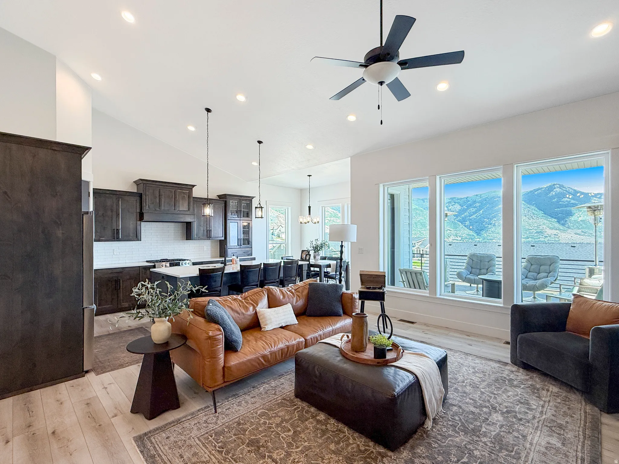 Spacious open-concept living area featuring high vaulted ceilings with recessed lighting, wood-finish flooring, and a ceiling fan