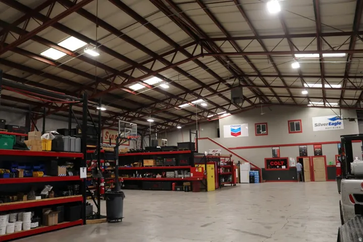 Spacious interior featuring a high trussed ceiling, multiple skylights, and fluorescent lighting