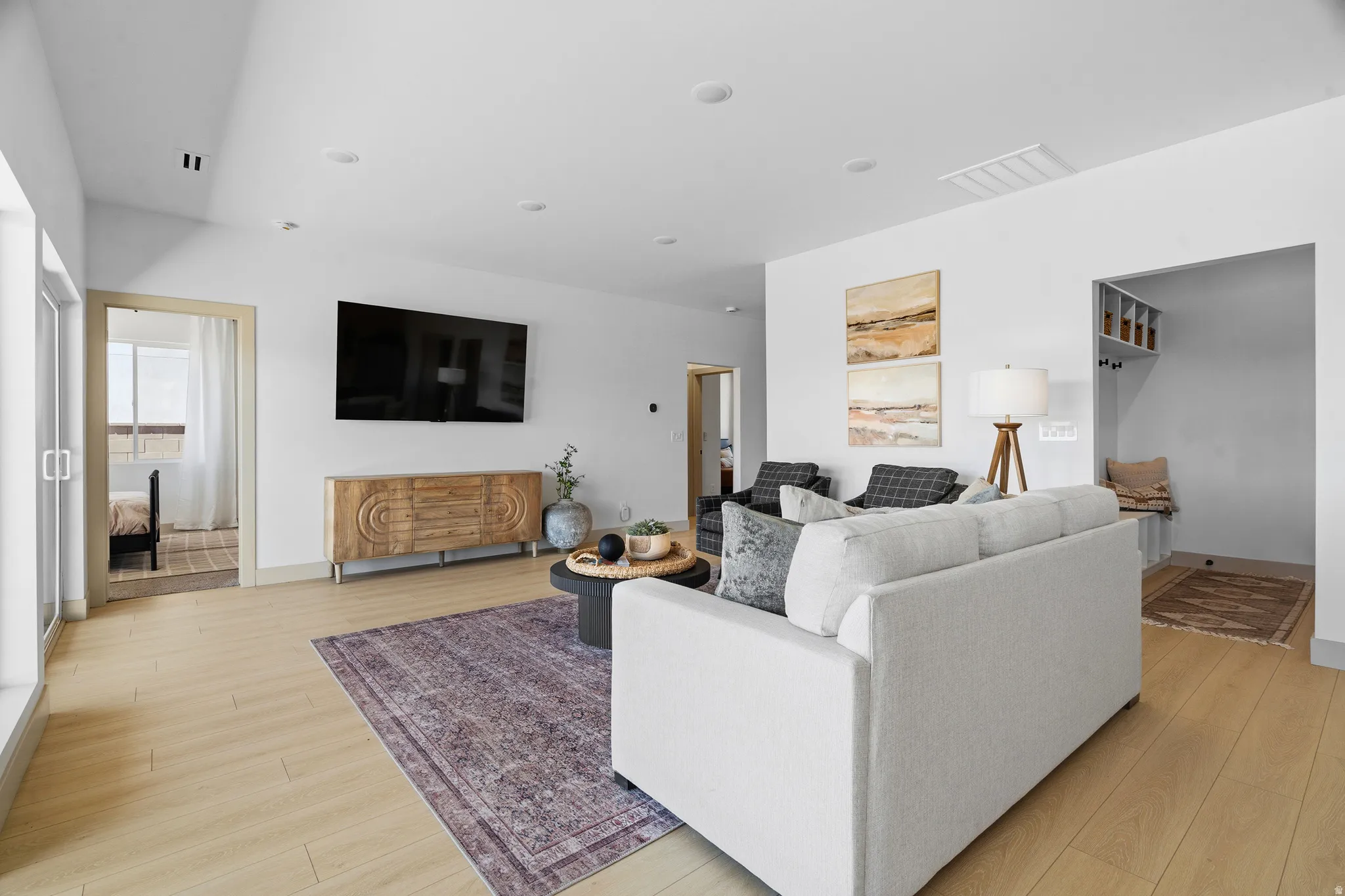 Spacious living area featuring light wood-finish flooring, recessed lighting, and white walls