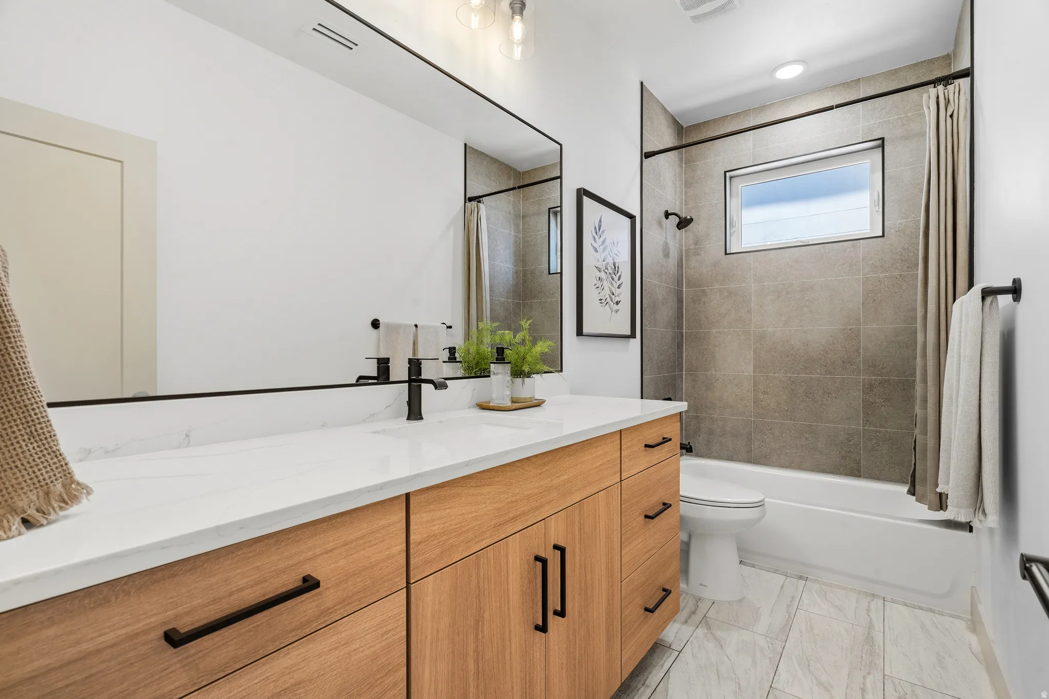 Bathroom featuring a wood-finish vanity with a quartz-style countertop and matte black hardware