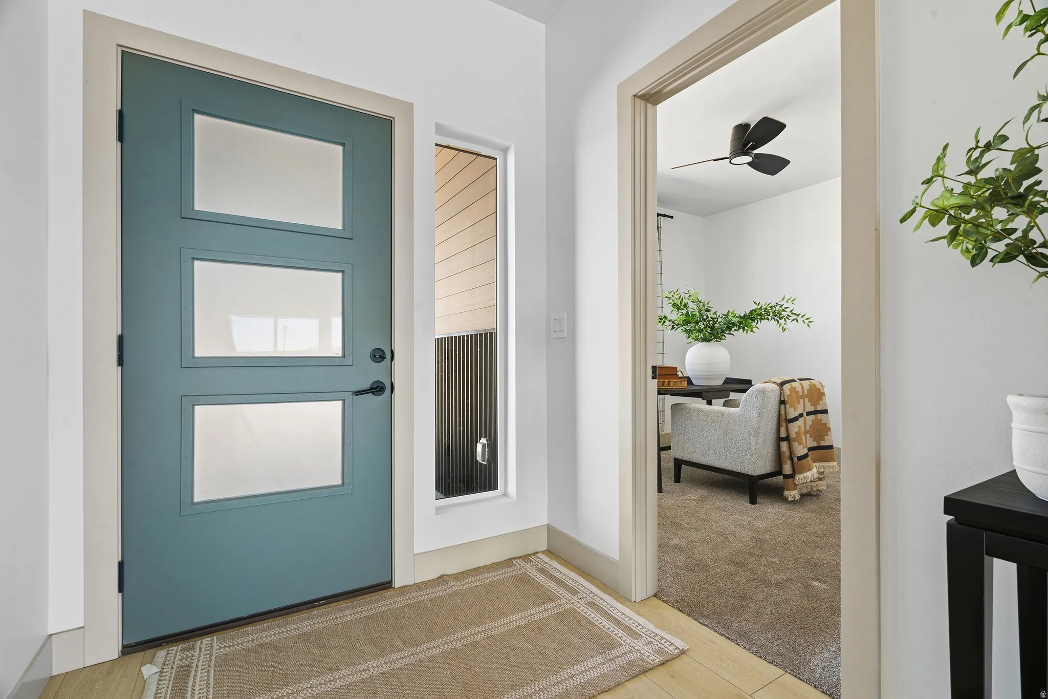 Modern entryway featuring a teal door with three lites, a vertical sidelite, and light wood-finish flooring