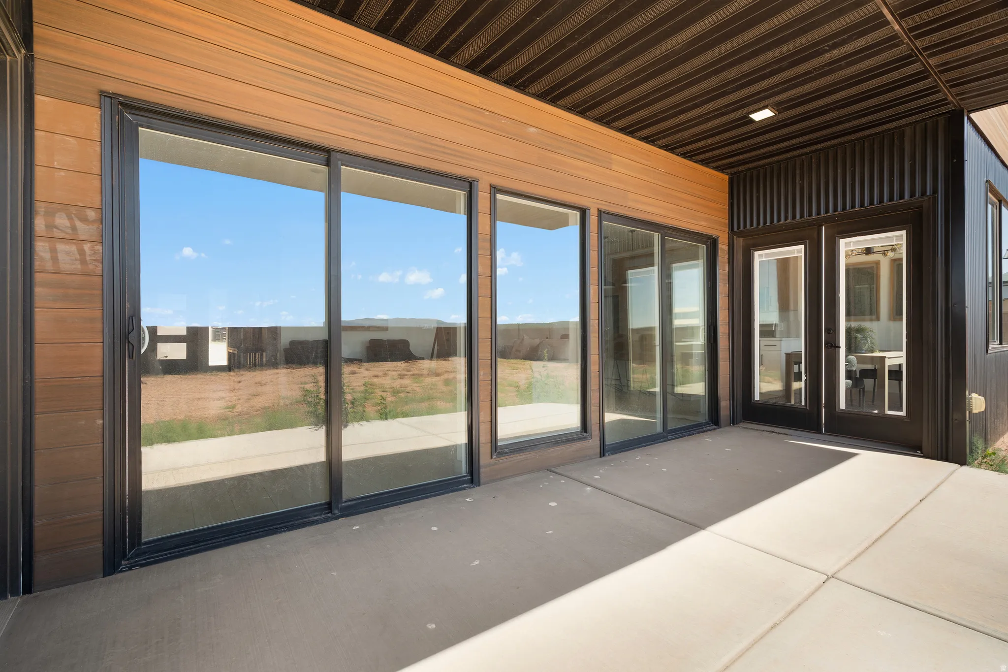 Expansive concrete patio area with a slatted wood-finish ceiling