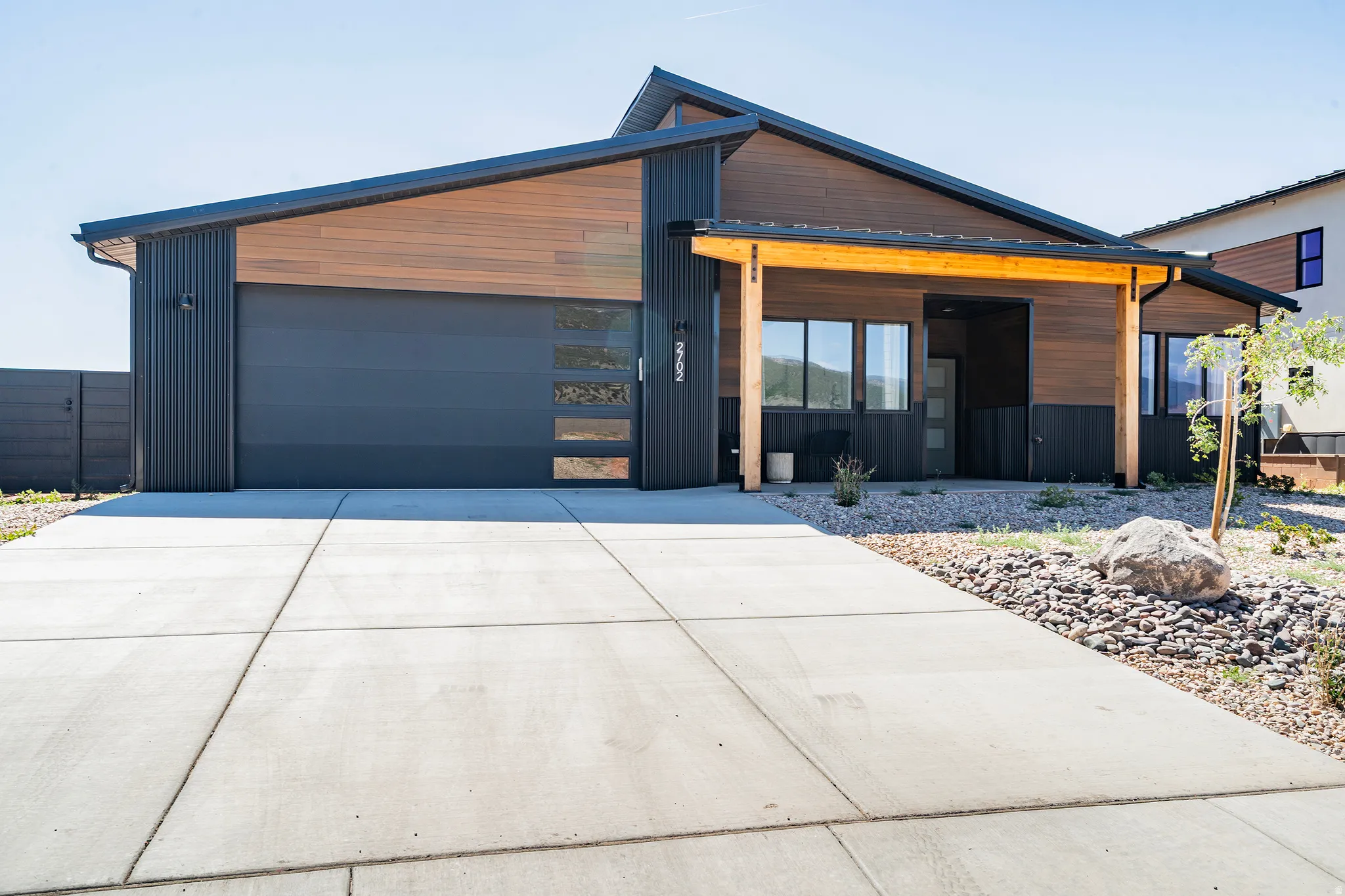 Contemporary exterior featuring a cantilevered roofline, wood-finish siding, and corrugated metal accents