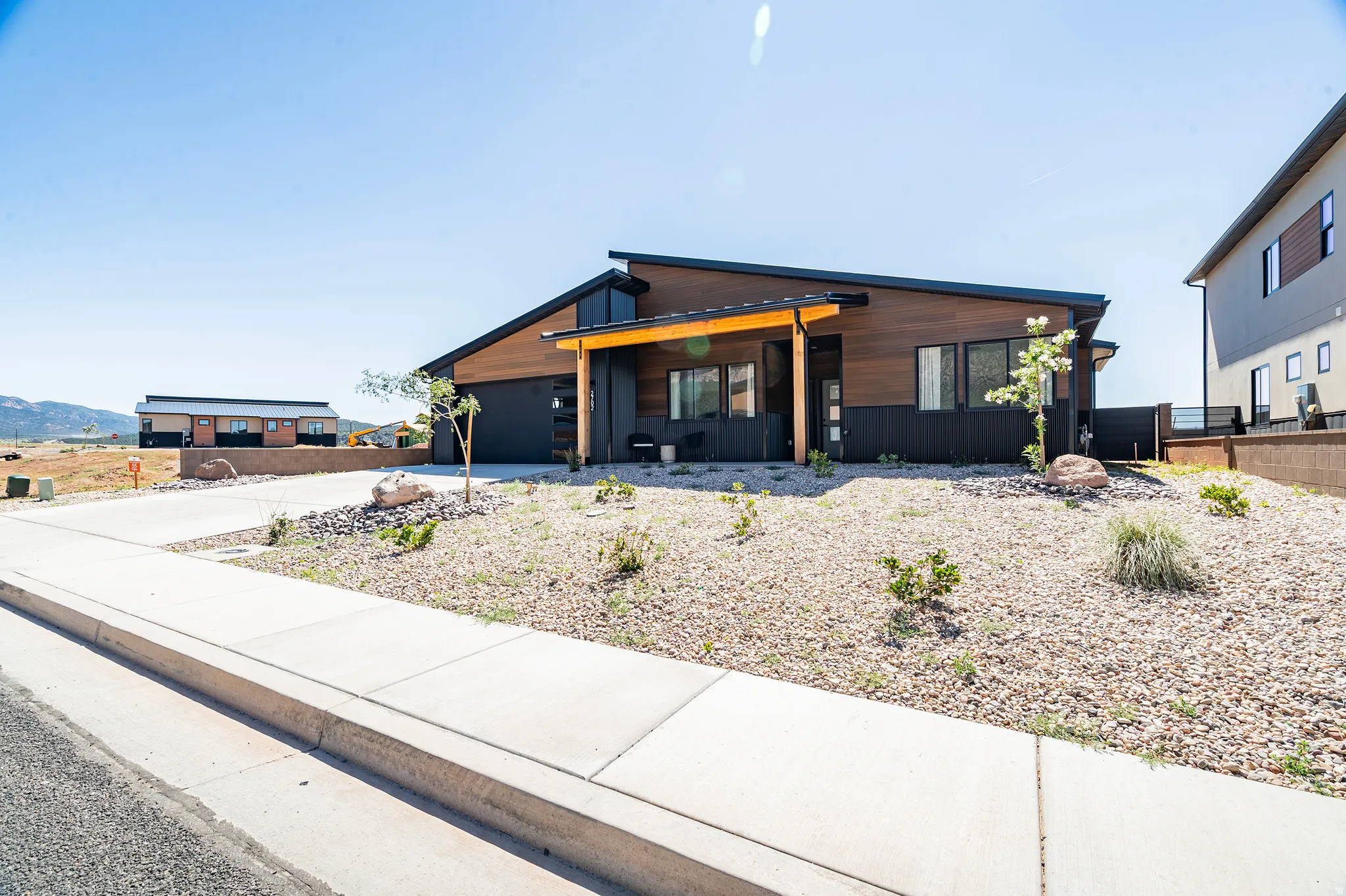 Contemporary exterior featuring wood-finish siding, dark accent panels, and a sloped roofline