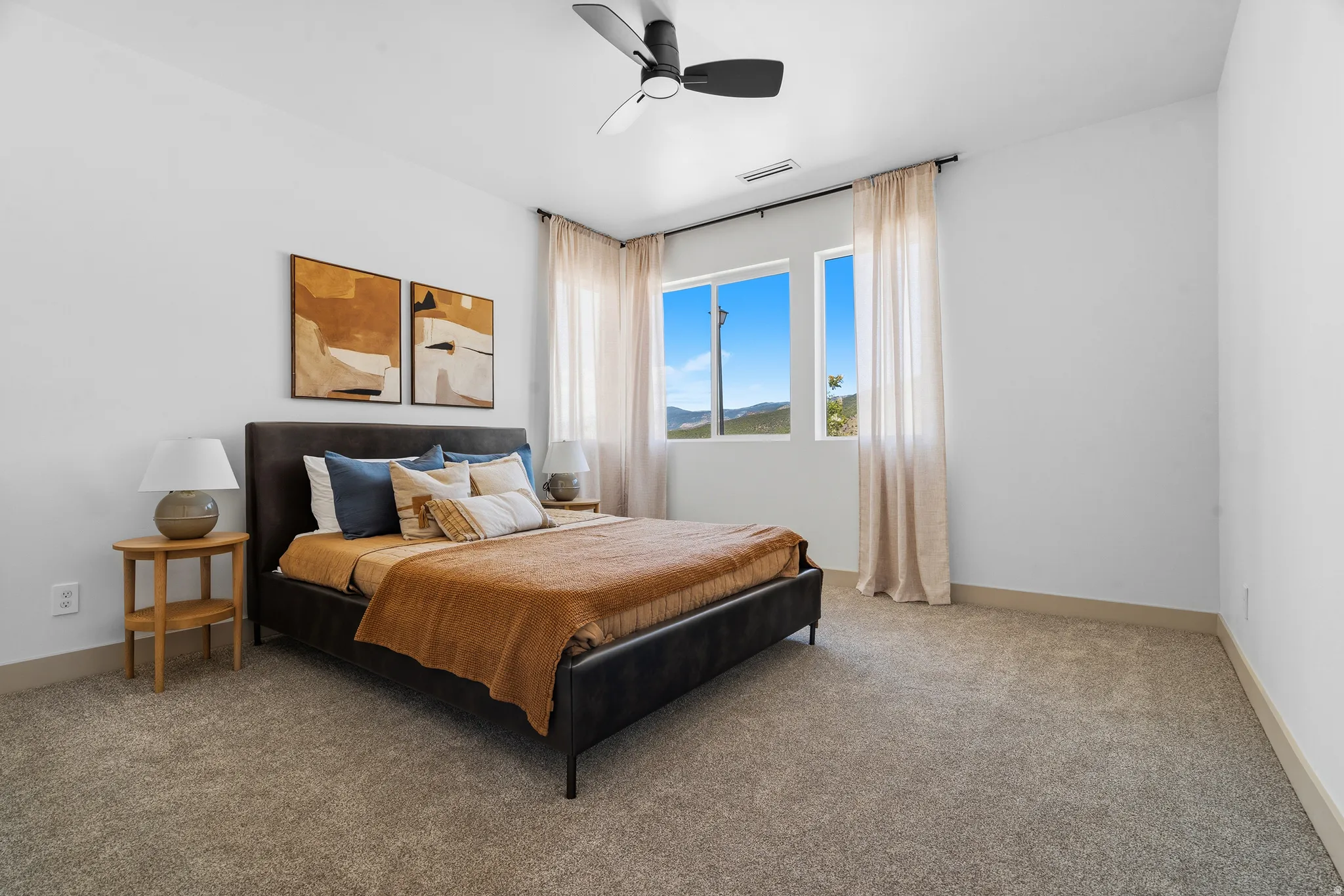 Room featuring a ceiling fan with light fixture, neutral carpeting, and a window with a mountain backdrop