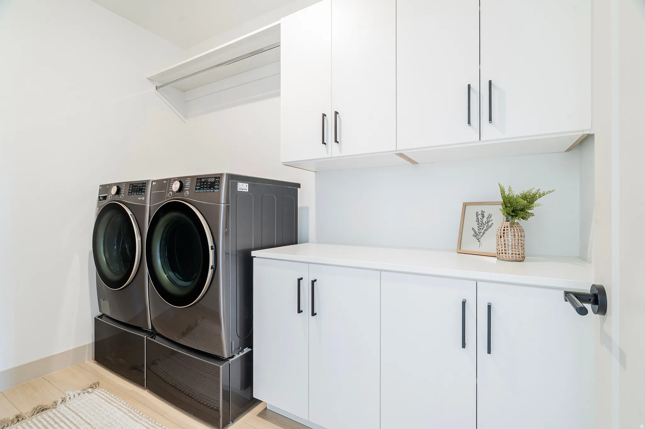 Dedicated laundry space featuring a white countertop and coordinating cabinetry with black hardware
