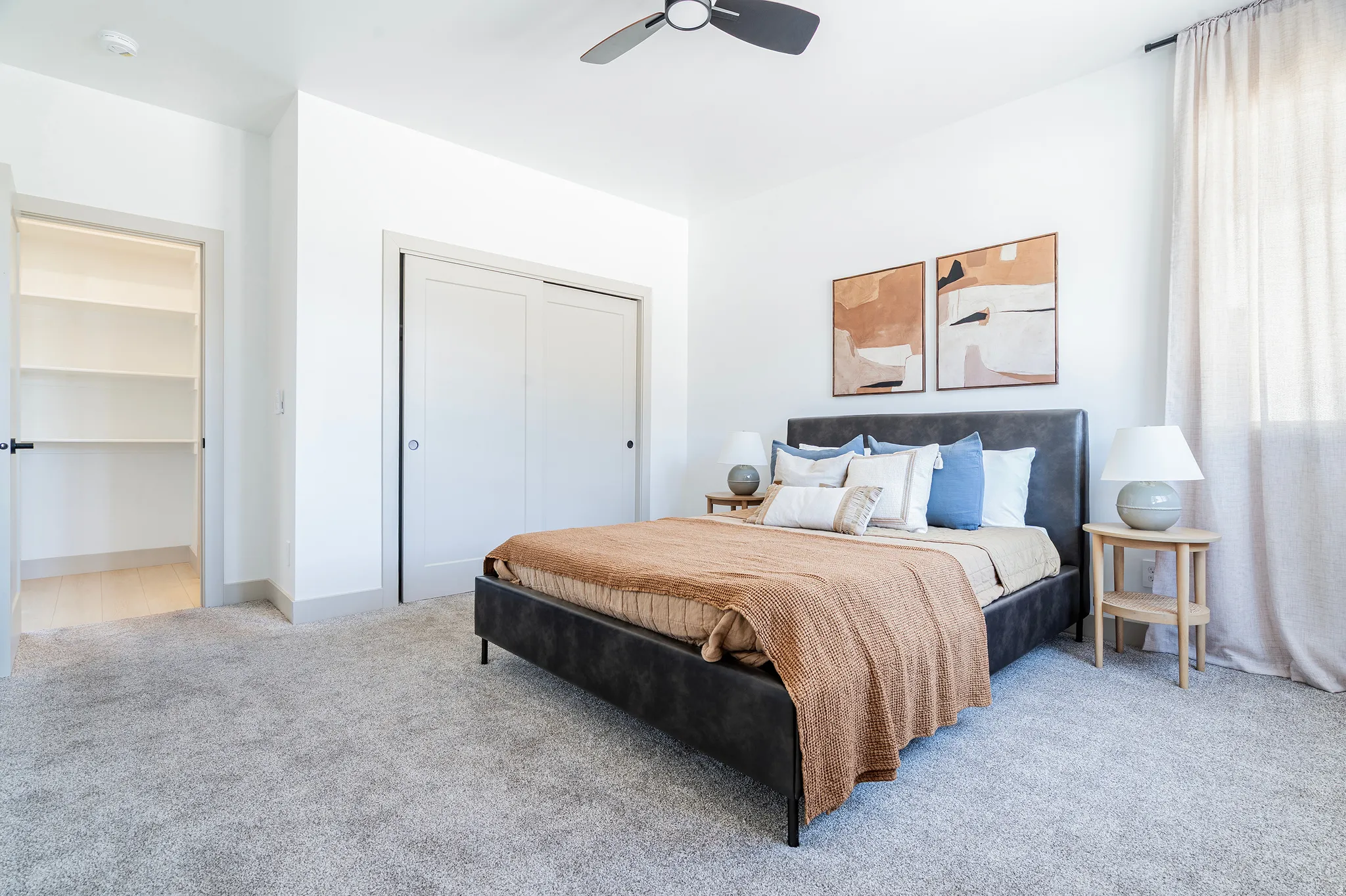 Spacious room featuring light-toned carpeting, white walls, and a ceiling fan