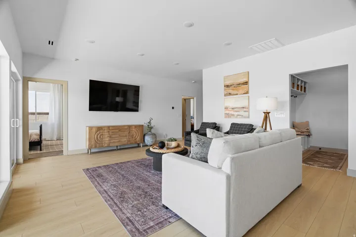 Spacious living area featuring light wood-finish flooring, recessed lighting, and white walls