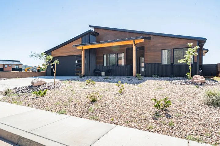 Modern architectural exterior featuring wood-tone and dark-paneled siding, a sloped roofline, and an integrated garage door