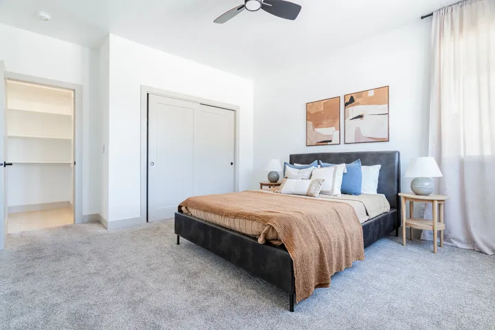 Spacious room featuring light-toned carpeting, white walls, and a ceiling fan