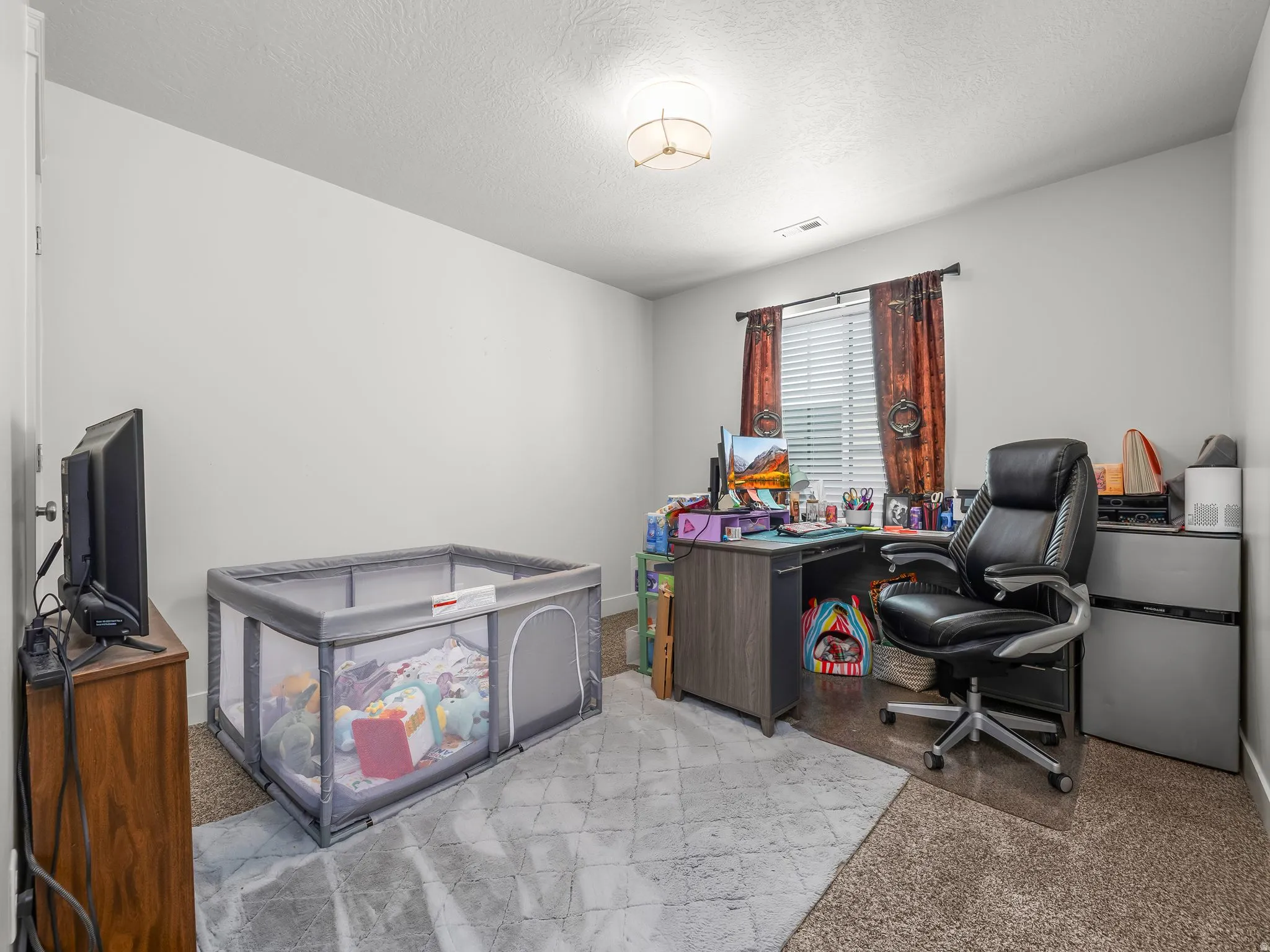 Bright room featuring a window with horizontal blinds, a neutral wall color, and a flush-mount ceiling light fixture