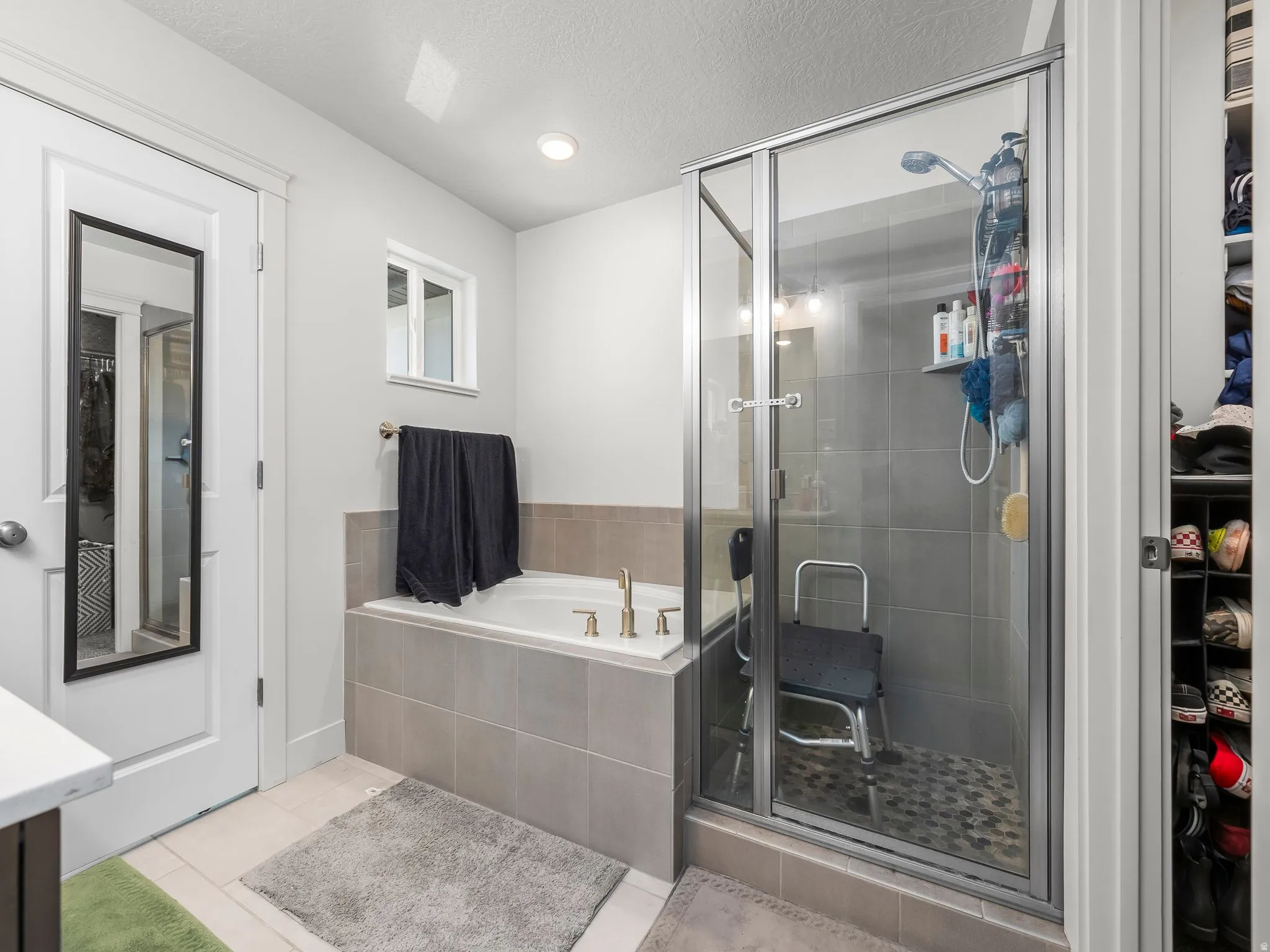 Bathroom featuring an enclosed shower with glass doors, a built-in tub with tile surround, and an integrated storage nook