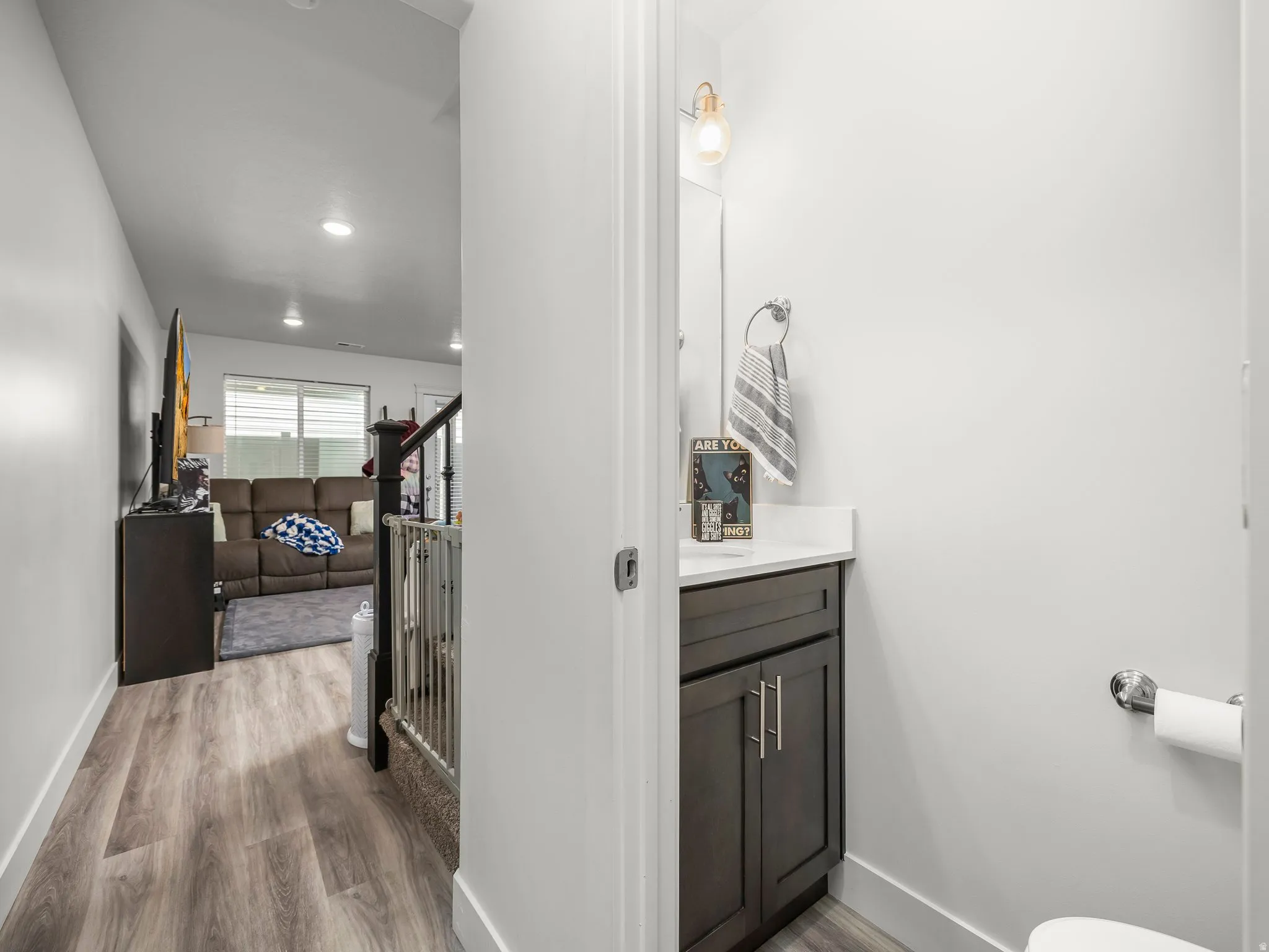 Powder room featuring a dark wood vanity with a white countertop, chrome hardware, and a single wall-mounted light fixture
