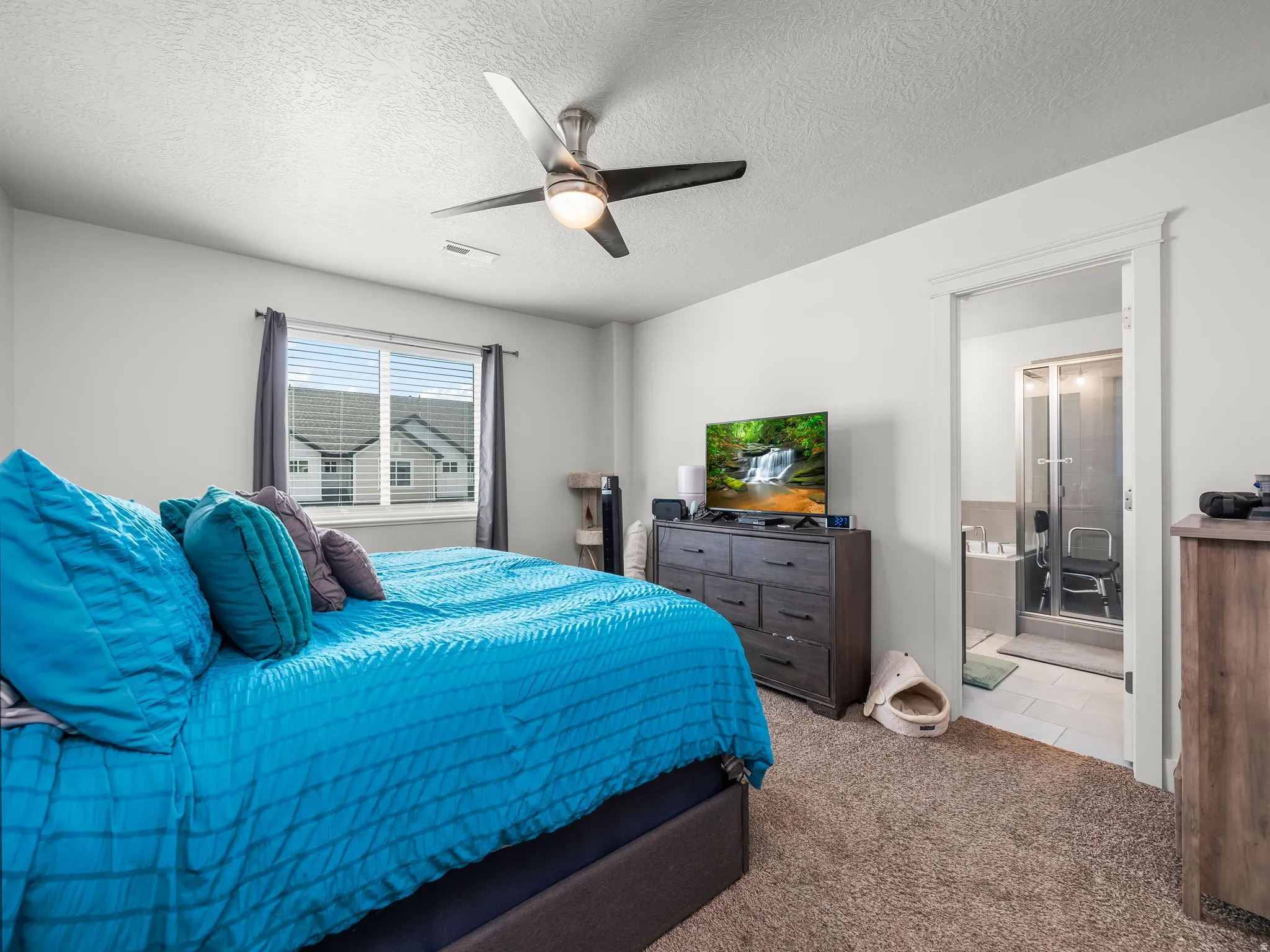 Carpeted bedroom with a ceiling fan light fixture and a window featuring horizontal blinds