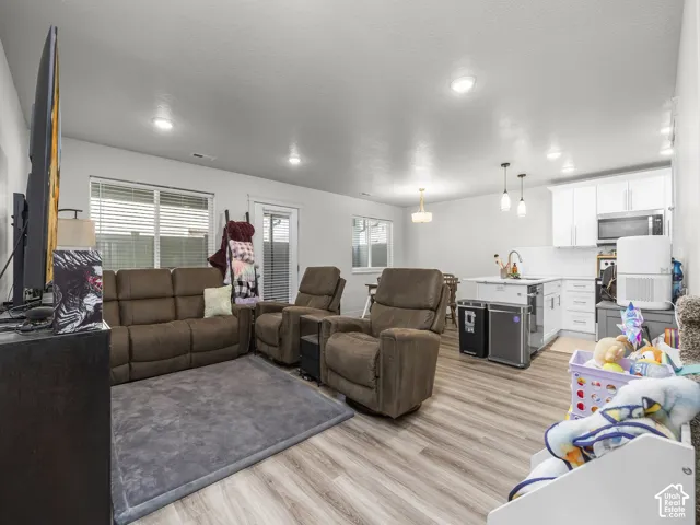 Open-concept living space featuring wood-finish flooring throughout, white walls, and recessed lighting