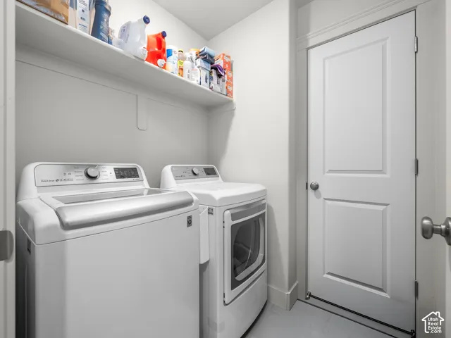 Laundry area featuring a built-in shelf, two permanent appliance hookups, a paneled interior door with a round knob, and light-toned flooring