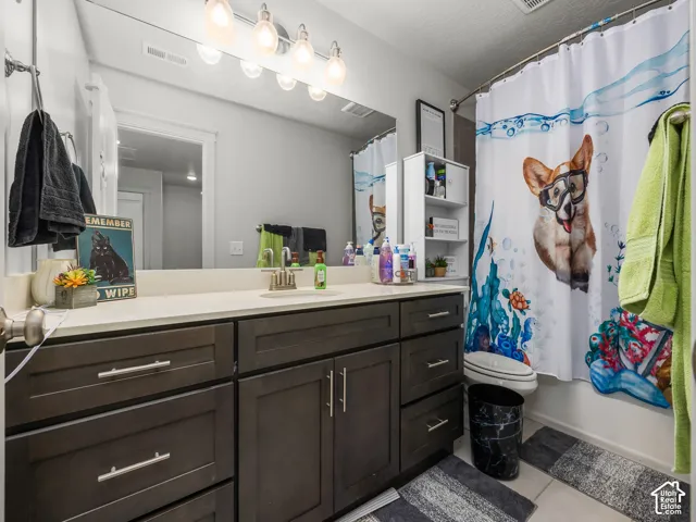 Bathroom featuring a dark wood-finish vanity with a light-toned countertop, a large wall-mounted mirror, and a built-in shower/tub combination