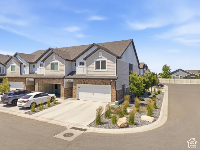 Contemporary townhome exterior featuring light-toned siding, dark shingle roofing, and brick accents