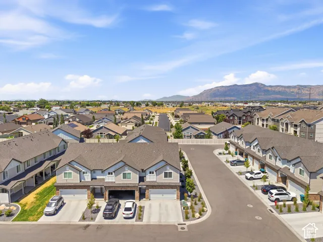 Modern townhome community featuring a paved street, attached garages, landscaping, and a mountainous backdrop