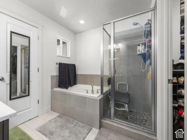 Bathroom featuring an enclosed shower with glass doors, a built-in tub with tile surround, and an integrated storage nook