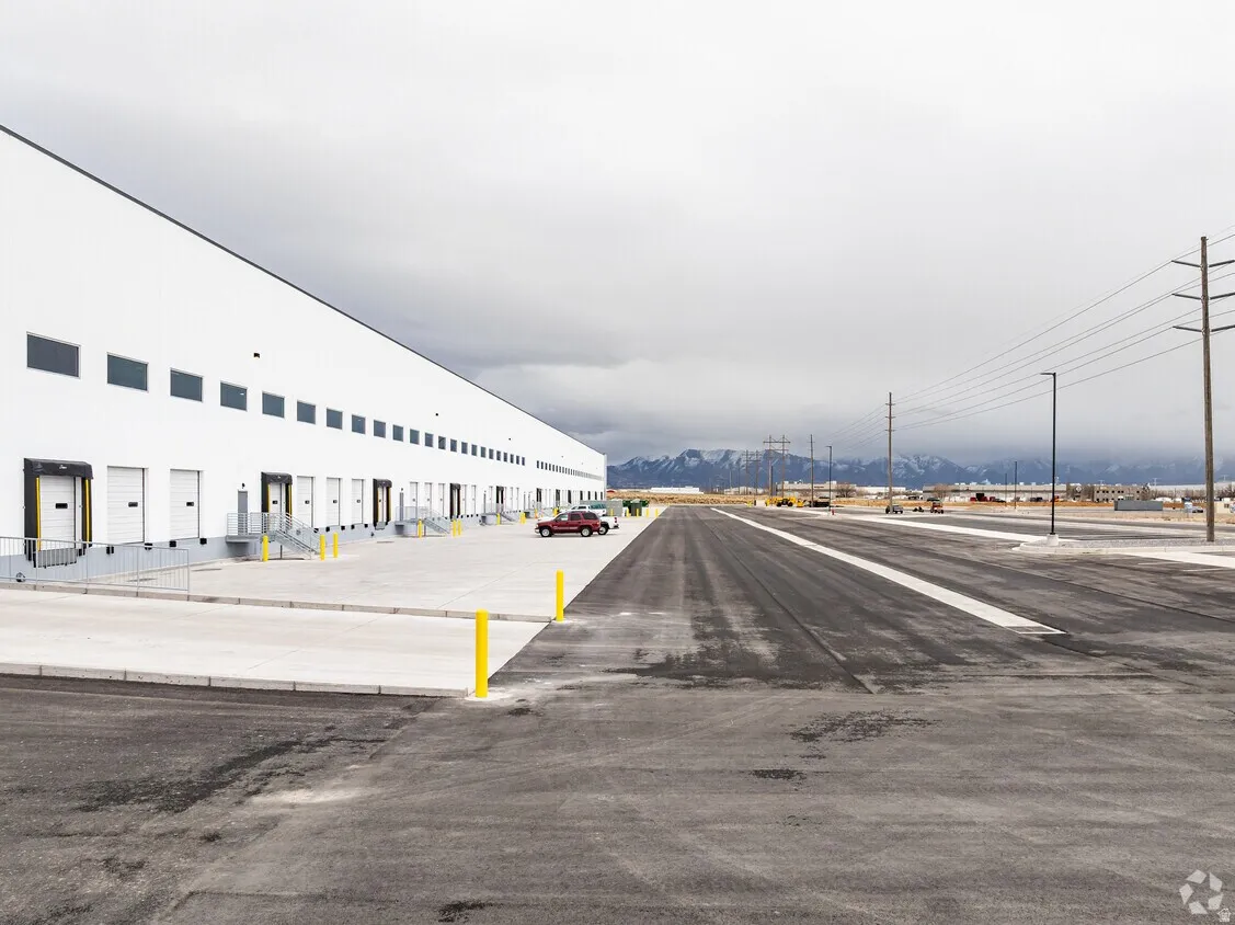 Expansive industrial facility featuring multiple loading dock doors, a large paved lot, and substantial exterior lighting
