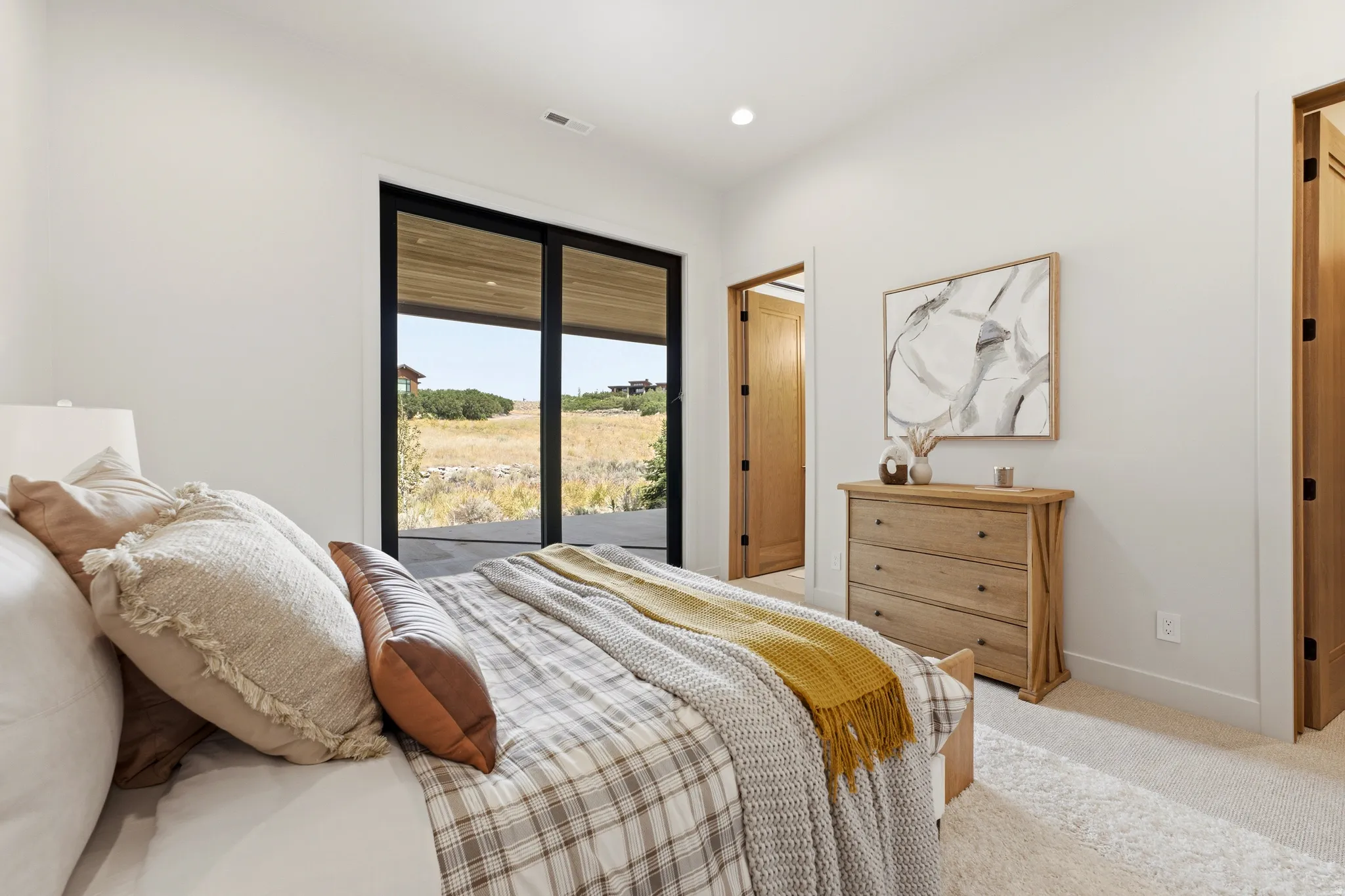 Sliding glass door, light wood-finish interior doors, recessed lighting, neutral wall color, and carpeted flooring