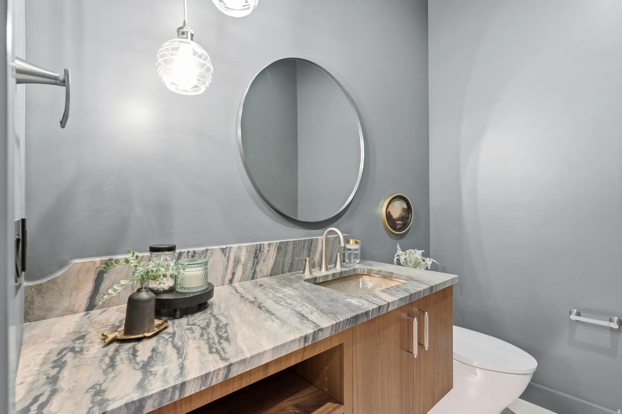 Vanity with an integrated sink, wood-finish cabinetry, and a stone countertop