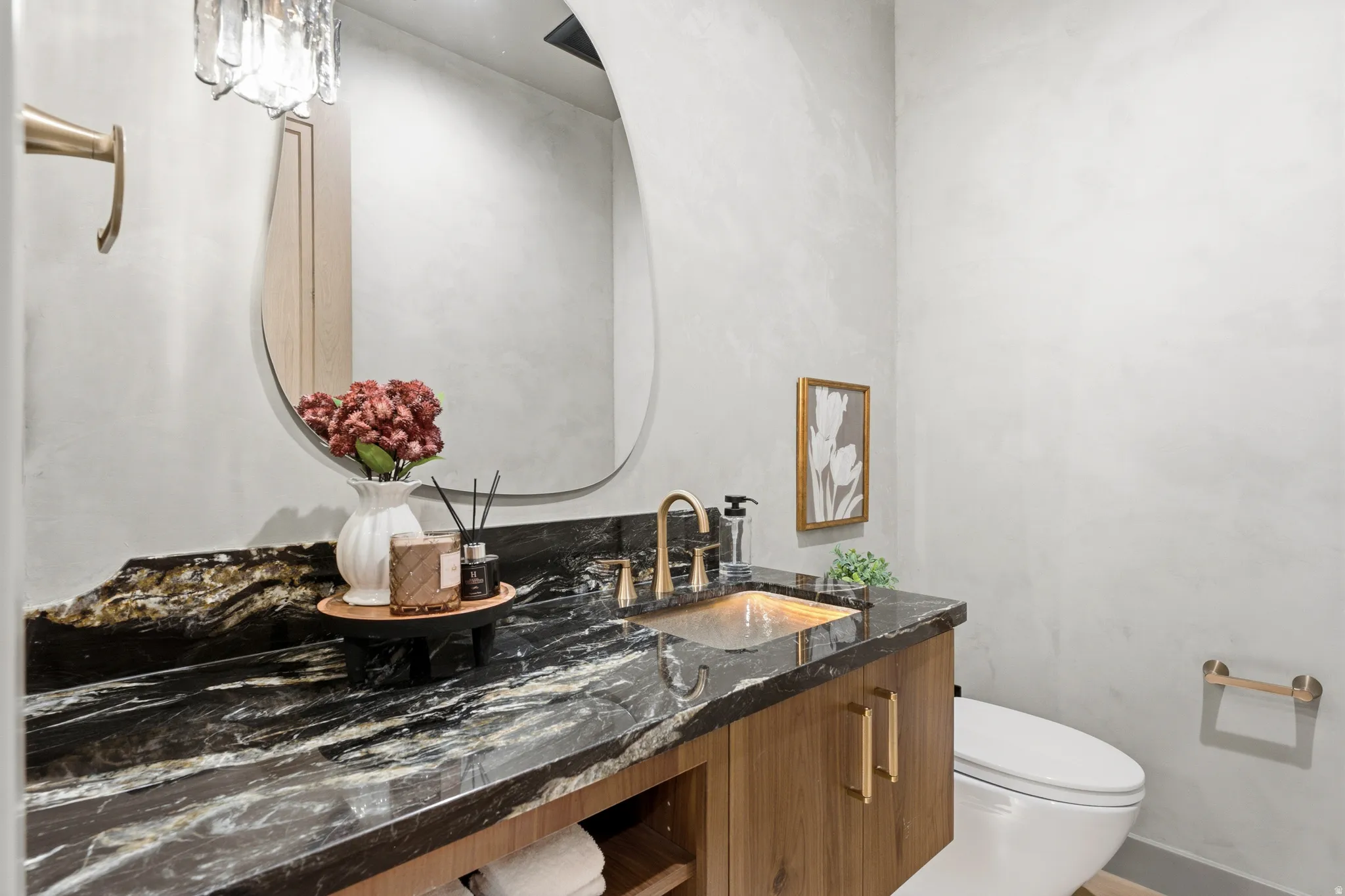 Vanity with a dark patterned countertop, integrated sink, and wood-finish cabinetry