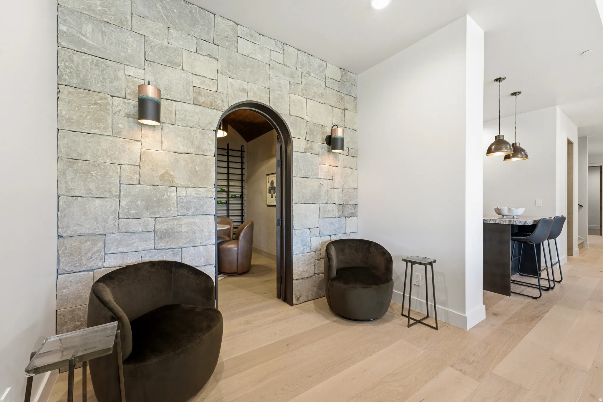 Stone accent wall with arched doorway, wood-finish flooring, recessed lighting, and pendant lighting
