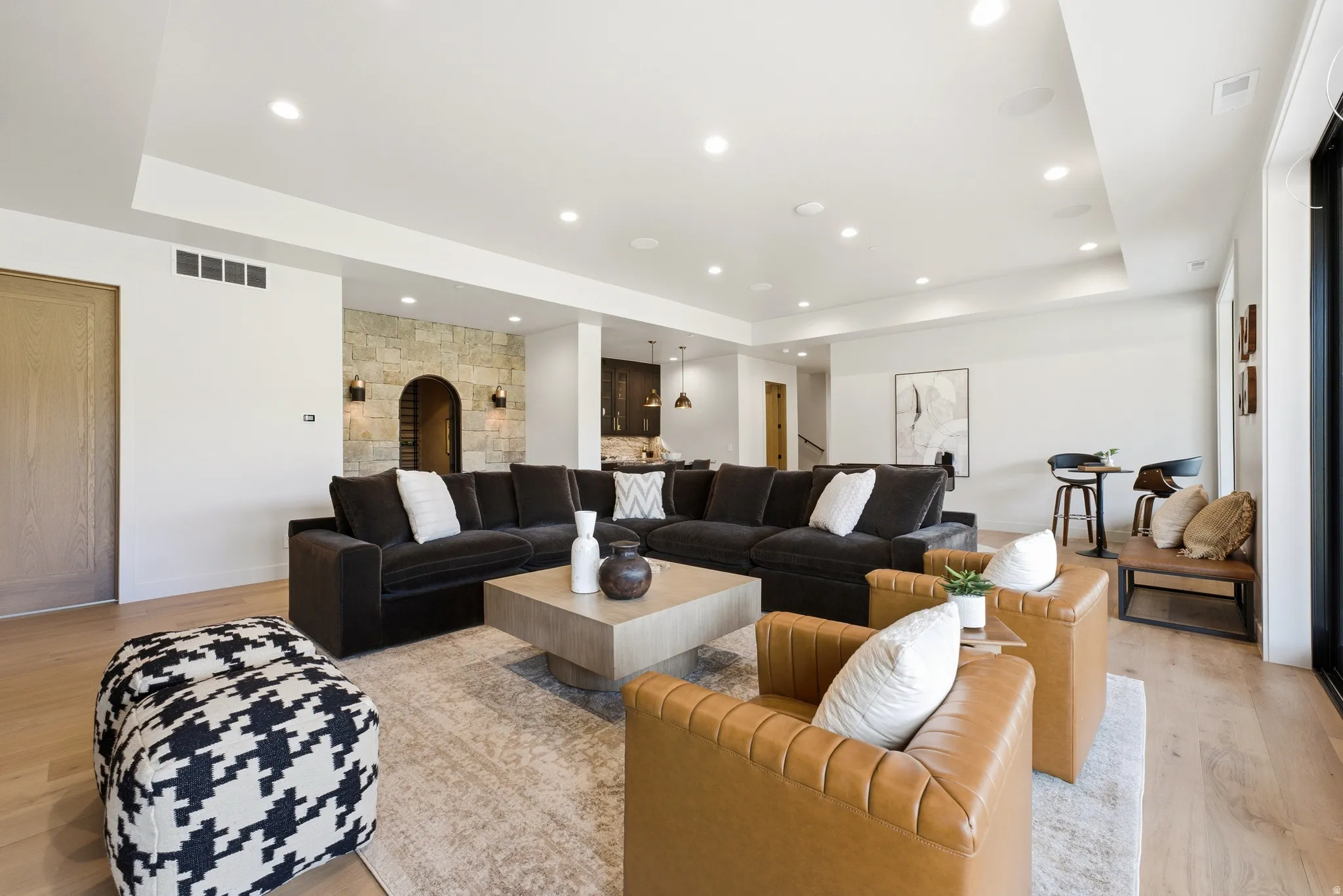 Recessed lighting, light wood-finish flooring, stone accent wall, arched doorway, and built-in ceiling speakers