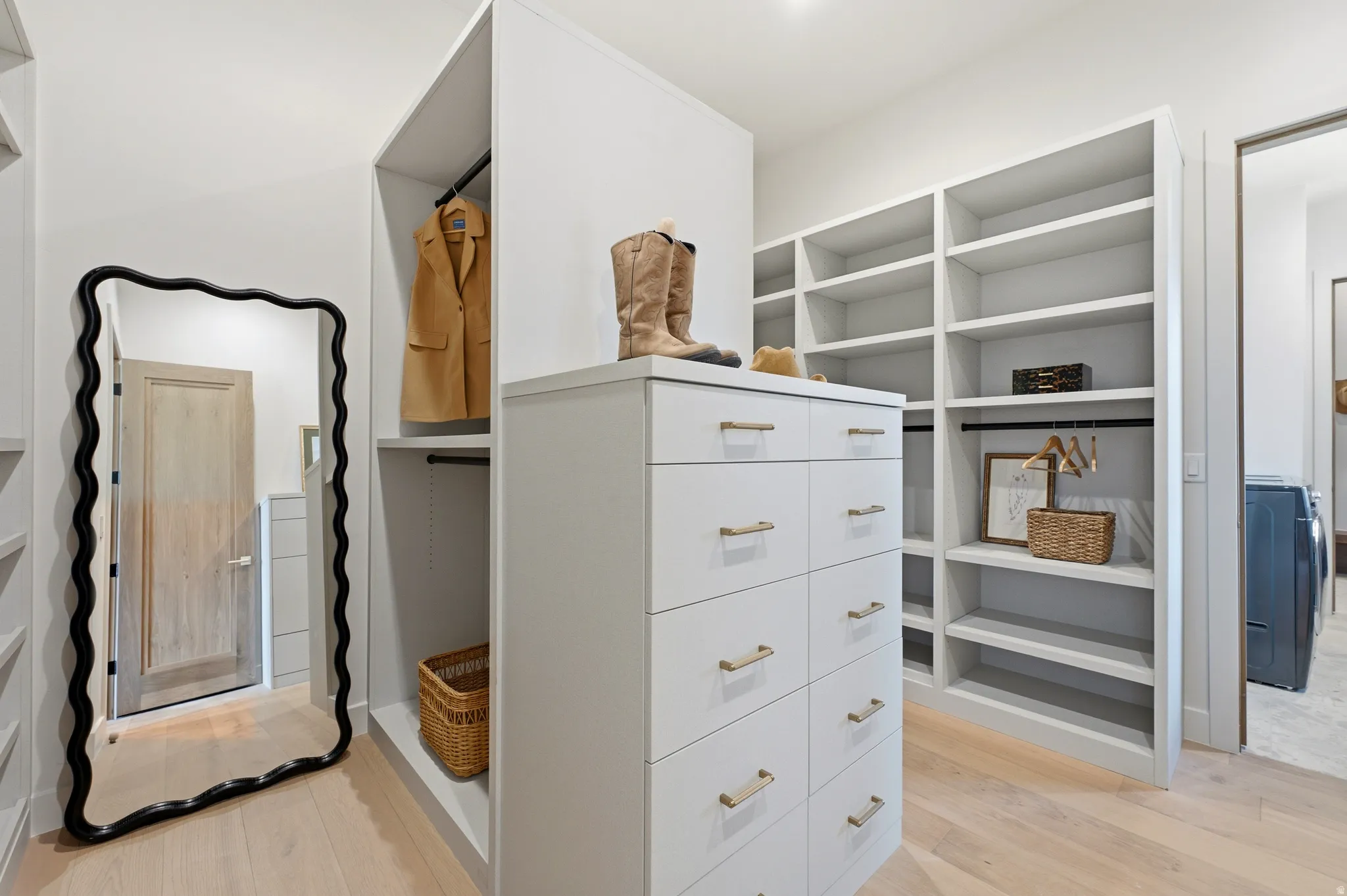 Custom closet system featuring built-in shelving, hanging rods, and a central drawer unit with gold-tone hardware