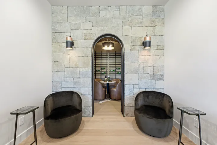 Stone accent wall with an arched doorway, light wood-finish flooring, and wall-mounted sconce lighting