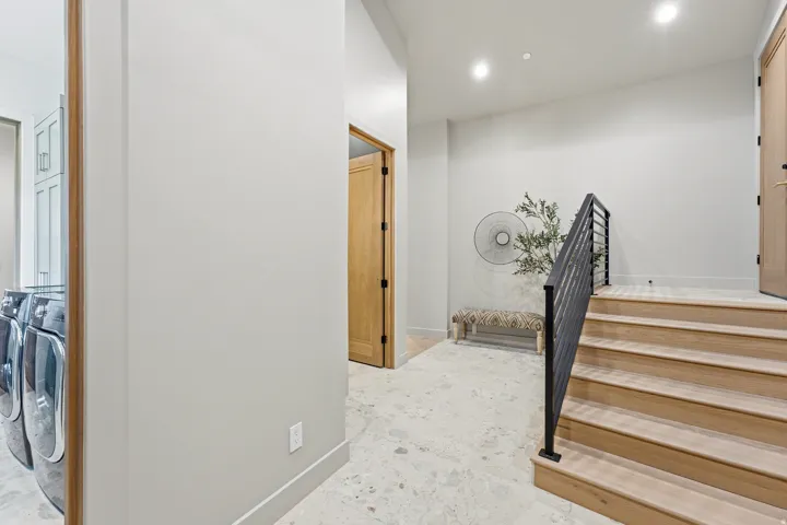 Hardwood staircase with metal railing, recessed lighting, wood doors, and light-toned flooring