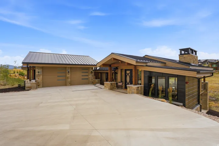 Contemporary exterior with stone accents, metal roof, and an expansive concrete driveway
