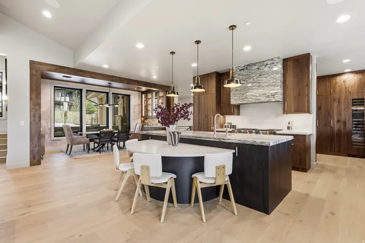 Open-concept kitchen with wood-finish flooring, a large island with seating, a built-in wine refrigerator, and dark wood cabinetry