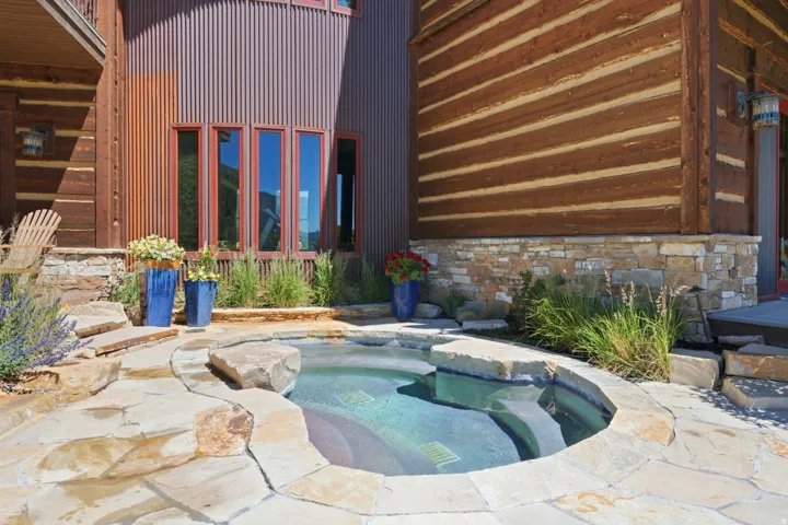 Outdoor spa with natural stone coping and integrated stone steps, surrounded by flagstone patio